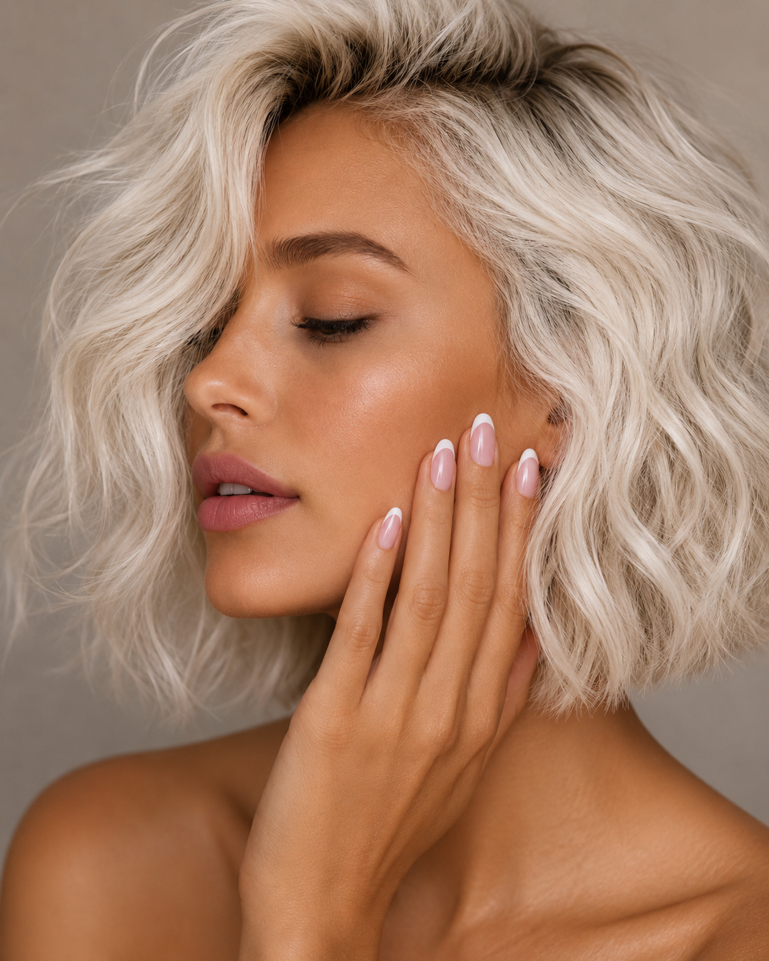 Woman with platinum blonde hair and pink filled ShadedbyShanell french tip press-ons touching her face against a neutral background