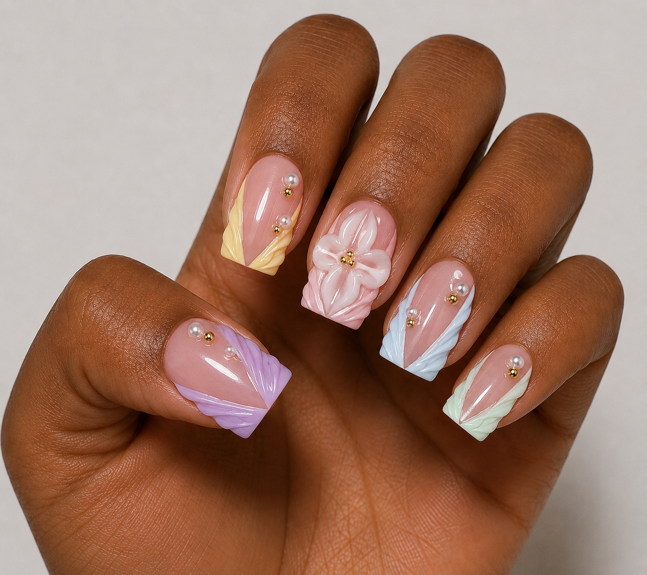 Hand with intricately designed nails featuring flowers and abstract patterns on a neutral background