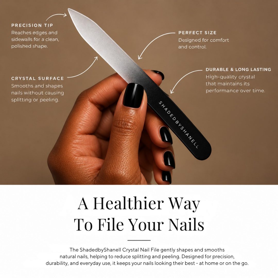 A hand with black nail polish holds a ShadedByShaneell crystal nail file against a warm brown background, with white text callouts highlighting the precision tip, crystal surface, perfect size, and durable long-lasting quality.