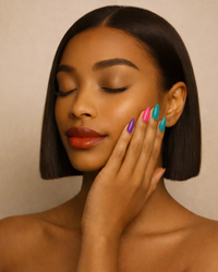 Woman with colorful ShadedbyShanell press-on nails touching her face against a beige background