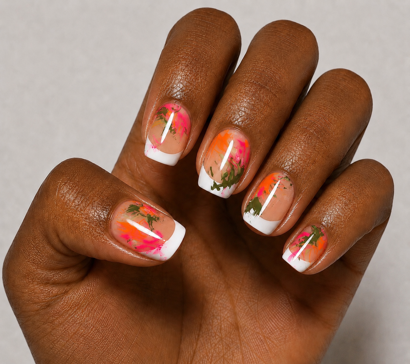 Hand wearing short tapered square french tip press-on nails with abstract art design