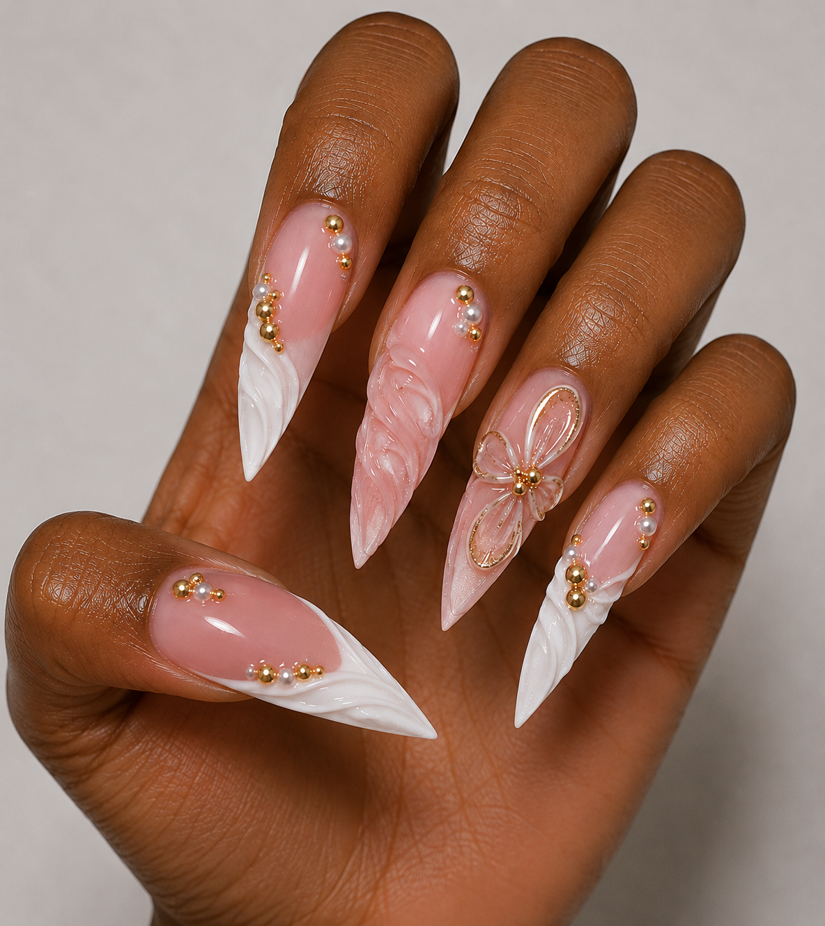 Hand with french press-on nails featuring flowers and pearls on a neutral background
