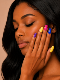 Woman with colorful ShadedbyShanell press-on nails holding her hand near her face against a beige background